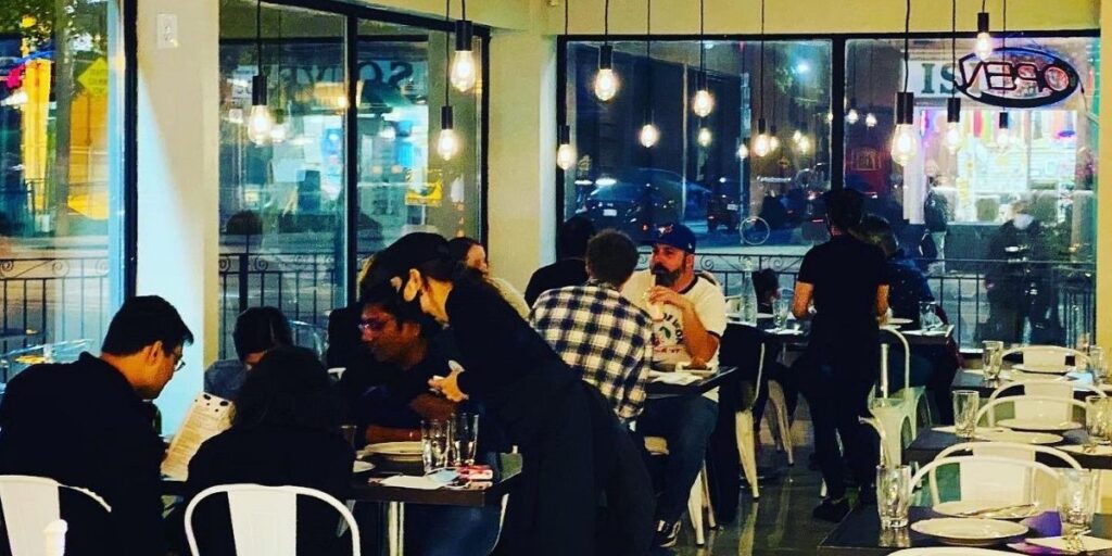 People enjoying meals at tables in a restaurant with large windows, featuring Punjabi cultural elements for an immersive dining experience.