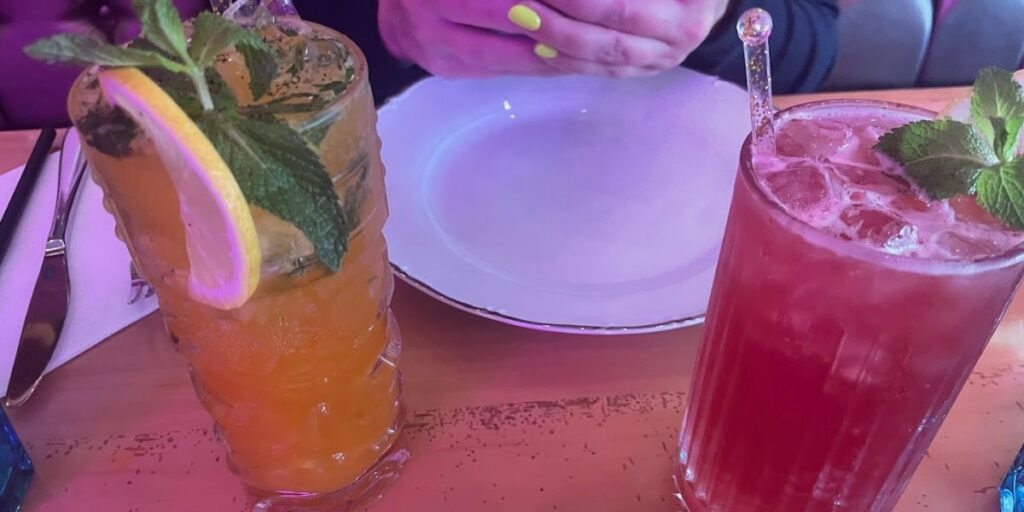 Two drinks on a table, one with a lemon slice, the other with a straw, surrounded by a cozy atmosphere.