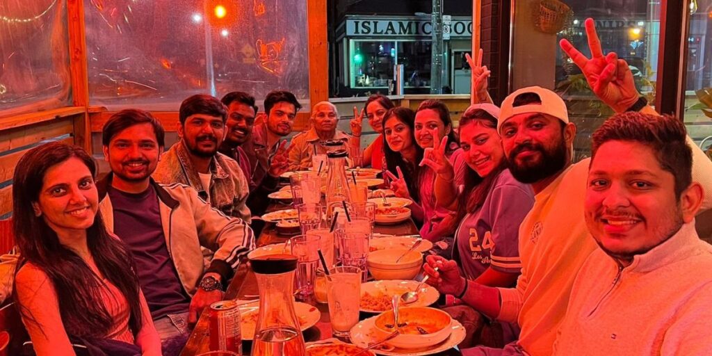 A group of people sitting at a table with food, enjoying a meal together.