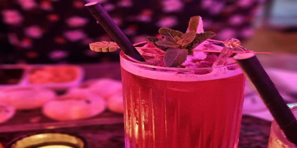 A glass of pink lemonade on a wooden table.