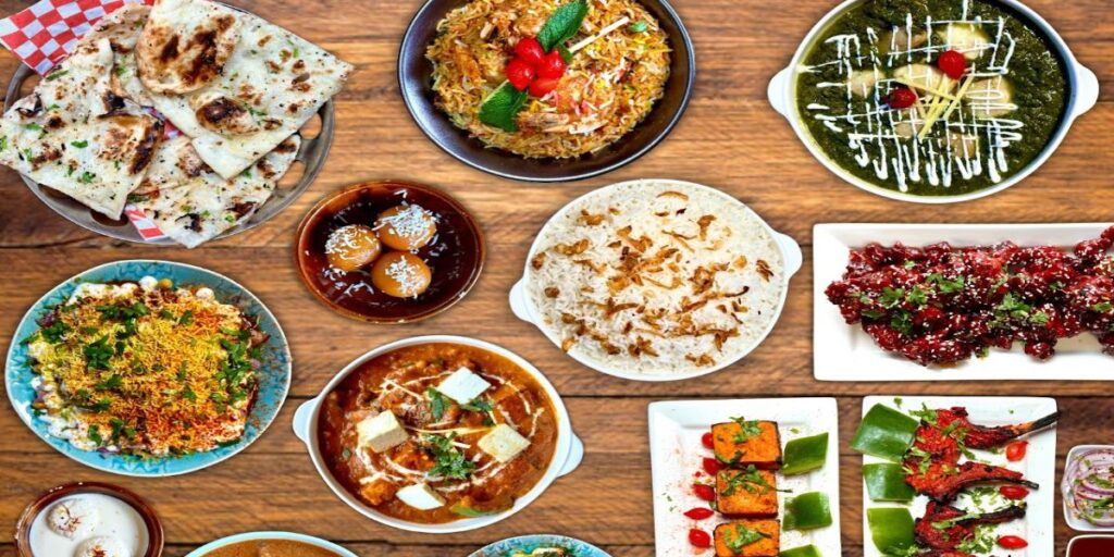 A selection of colorful dishes displayed on a wooden table, including salads, pasta, and grilled vegetables.