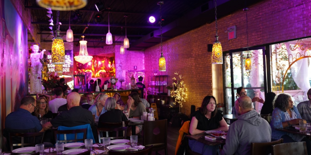  Group of people enjoying dinner at restaurant with purple lights.