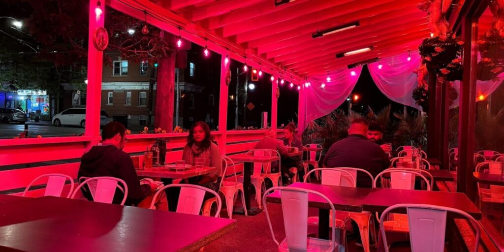 People dining at Leela Indian Food Bar, with pink lighting, enjoying authentic Punjabi cuisine in Toronto.