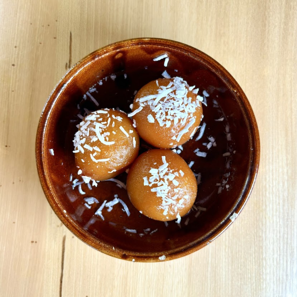 Three Gulab Jamun of dough, generously coated in coconut, showcasing a sweet treat perfect for dessert.