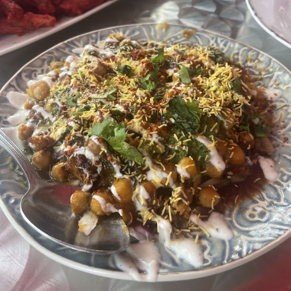 A plate of hot snacks featuring a variety of small dishes, accompanied by a spoon for serving or tasting.