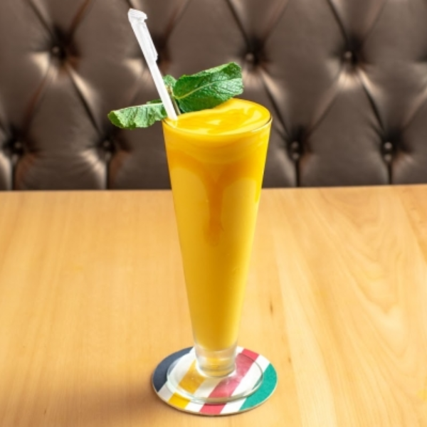 A refreshing glass of Lassi with a straw, showcasing its vibrant color and inviting appearance.