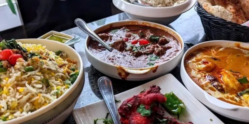 A vibrant display of Indian cuisine served in bowls and plates, featuring diverse and flavorful main courses for a wedding feast.