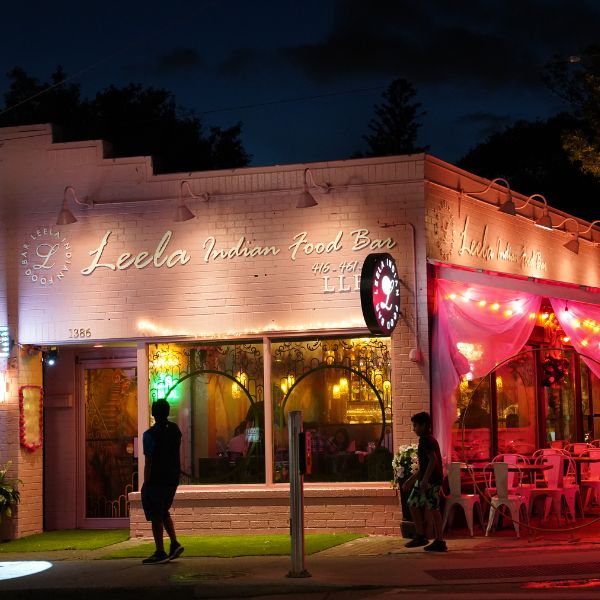 A vibrant restaurant exterior featuring a neon sign, inviting guests to experience Leela Indian Food Bar on Gerrard Street.