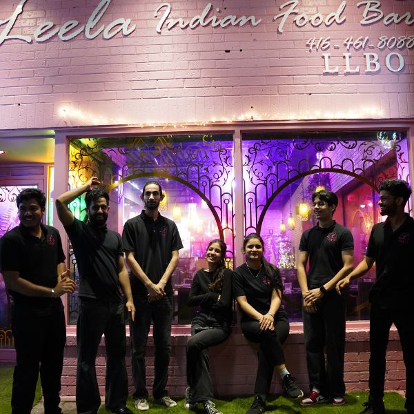 A diverse group of people gathered outside Leela Indian Food Bar, showcasing community spirit on Gerrard Street.