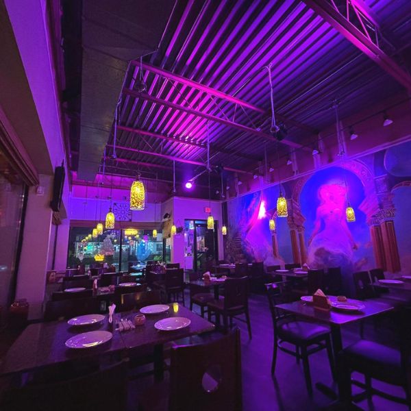 A vibrant restaurant interior featuring purple walls and lighting, showcasing Leela Indian Food Bar's inviting atmosphere.