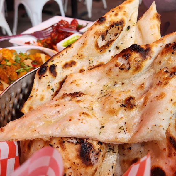 A basket of assorted naan bread on a table, showcasing its soft texture and warm, inviting appearance.