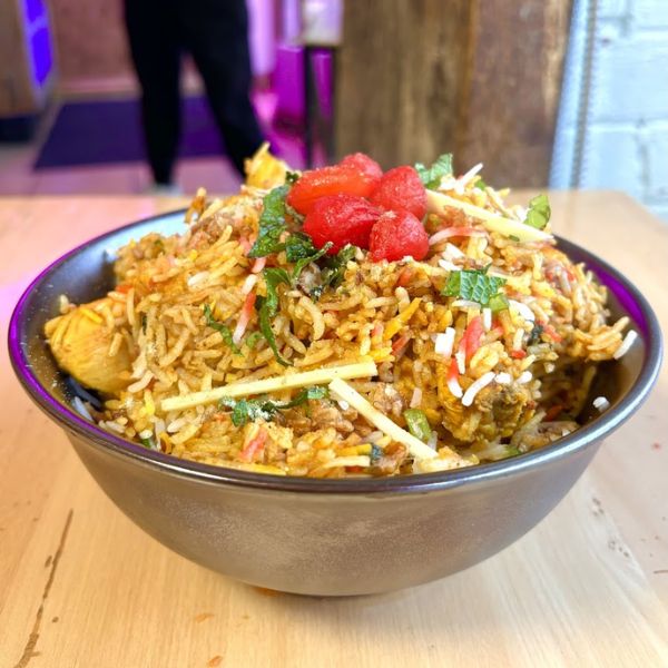 A bowl of rice and vegetables on a wooden table, showcasing a colorful and flavorful meal.